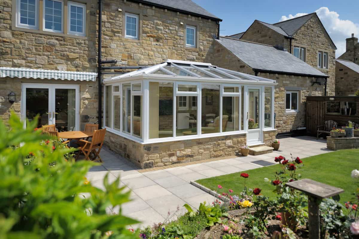 Modern conservatory with glass walls and roof in a residential garden.